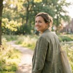 Ontspannen vrouw kijkt glimlachend achterom tijdens een wandeling in de natuur, vrij van sociale angst na hypnose in Boxmeer.